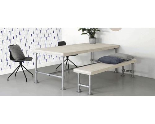 Jedálenský stôl s lavicou a stoličkami vo svetlej miestnosti s geometrickou tapetou.