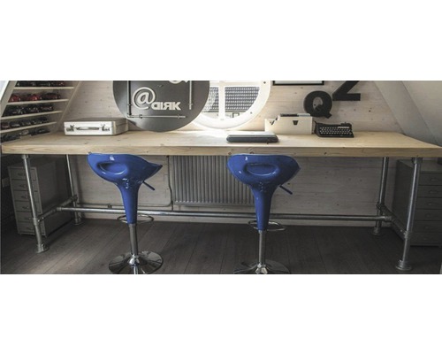 Svetlá podkrovná izba s dreveným písacím stolom, rúrkovým rámom a dvoma barovými stoličkami.