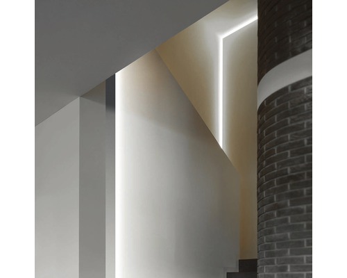 Interiérová snímka schodiska s lineárnymi svetelnými prvkami a stĺpom z tehál.