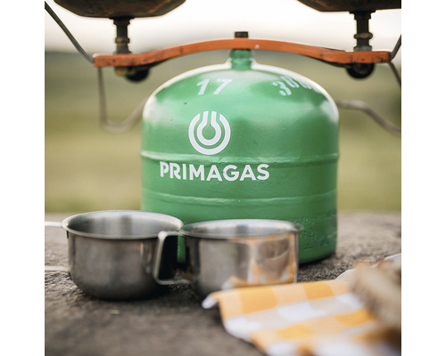 Zelená propánová fľaša od spoločnosti Primagas vedľa dvoch kovových šálok