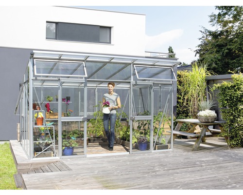 Skleník Vitavia Aphrodite 11500 kombinácia skla a polykarbonátu 275x396 cm hliník Skleník s rastlinami a ženou v záhrade