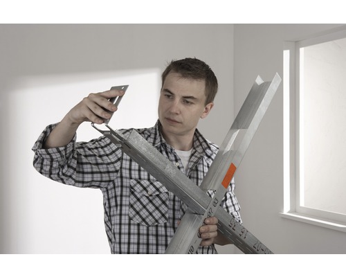 Muž montuje kovový profil pomocou rohového konektora.