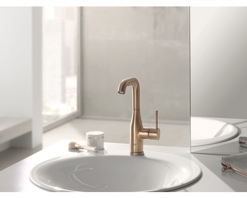 Na umývadle stojí zlatá vodovodná batéria vedľa umývadla.