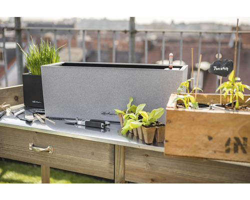 Scéna s osadzovacím stolom, kvetináčmi a záhradným príslušenstvom pre vonkajšie použitie.