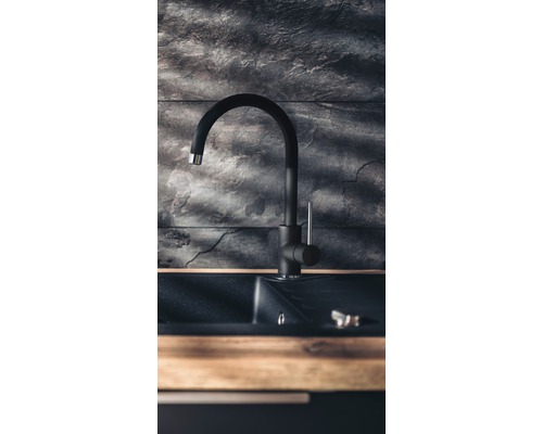 Čierna kuchynská batéria s drezom pred kamennou stenou