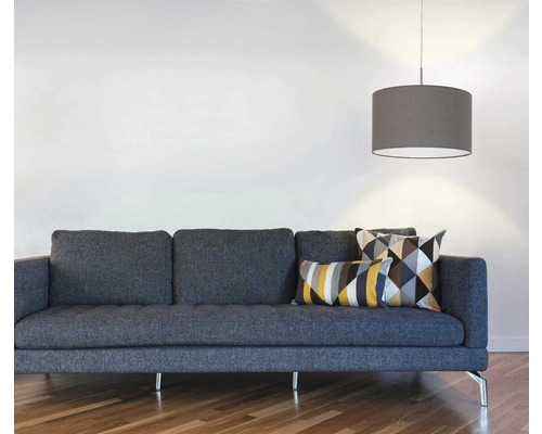 Obývacia izba so sivou pohovkou, geometrickými vankúšmi a závesnou lampou