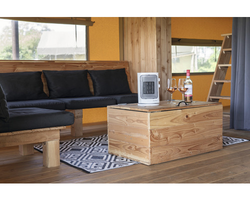 Interiér stanu s dreveným nábytkom, vykurovacím ventilátorom a fľašou vína s pohármi