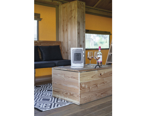 Interiér s dreveným nábytkom, prenosným ohrievačom a dvoma pohármi vína na drevenom stole