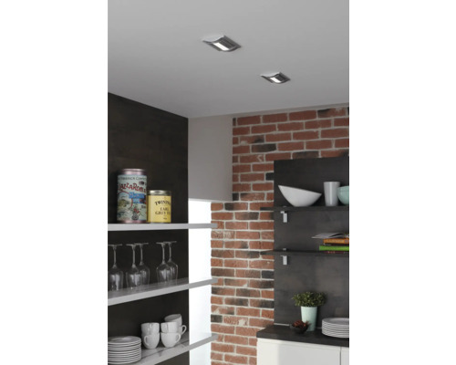 Kuchynská scéna so stropnými bodovými svietidlami, tehlovou stenou a otvorenými policami s riadom