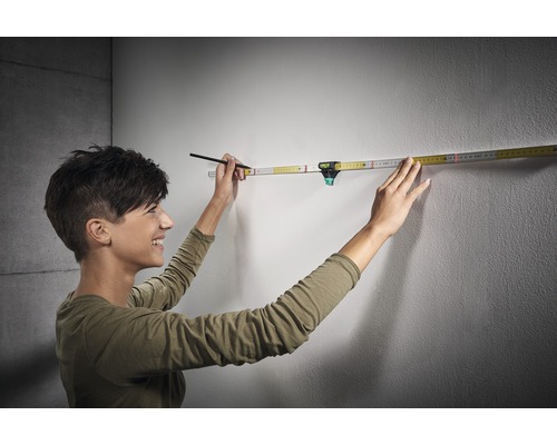 Žena používa skladací meter s integrovanou vodováhou na stene