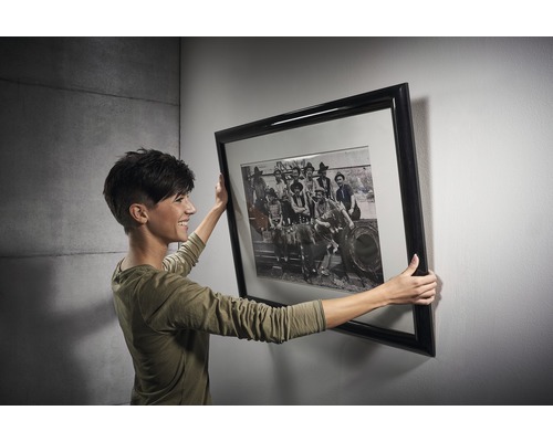 Žena drží zarámovanú umeleckú tlač na stene