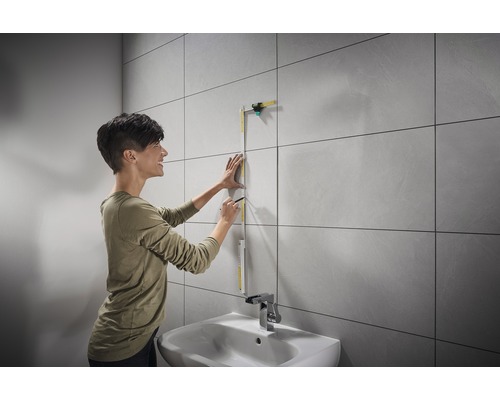 Žena meria stenu skladacím metrom v kúpeľni