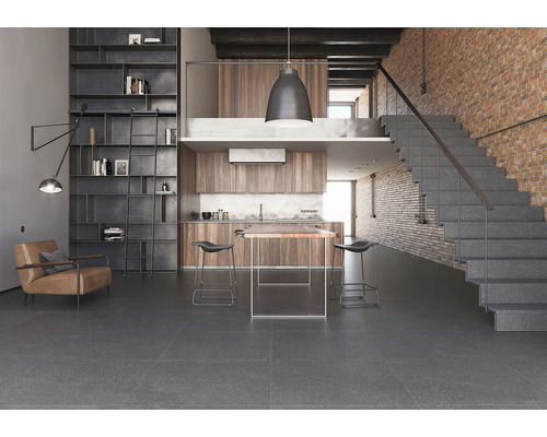 Svetlá izba s regálmi, posedením, kuchyňou, jedálenským stolom, barovými stoličkami a schodiskom s kamenným vzhľadom.