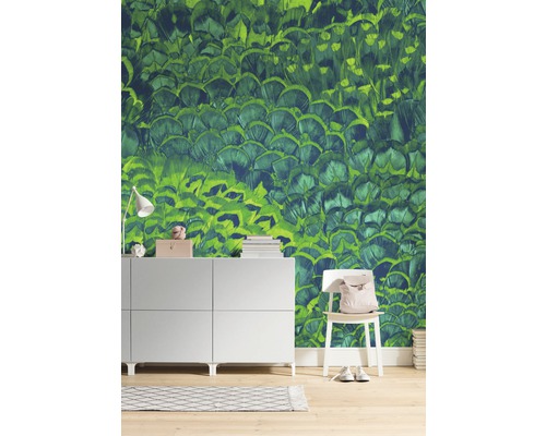 Obývacia izba so zelenou tapetou s motívom peria, komodou a stoličkou