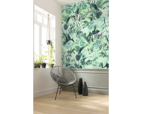 Zdobená izba s tapetou s motívom džungle, okrúhlou stoličkou a izbovými rastlinami