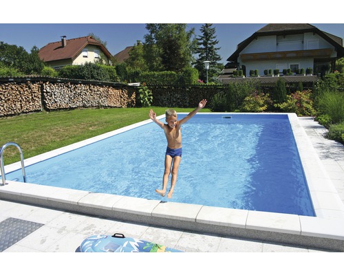 Chlapec skáče do obdĺžnikového bazéna v záhrade.