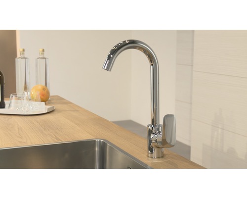 Kuchynská vodovodná batéria z kovu pri dreze na pracovnej doske