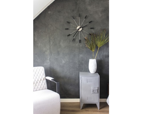 Interiérová fotografia izby s kreslom, hodinami, vázou s rastlinami a kovovou skriňou