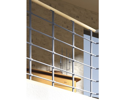 Kovové zábradlie s dreveným držadlom pred tehlovou stenou