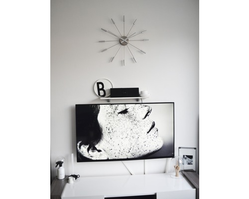 Obývacia izba s televízorom, nástennými hodinami a dekoráciami na skrinke