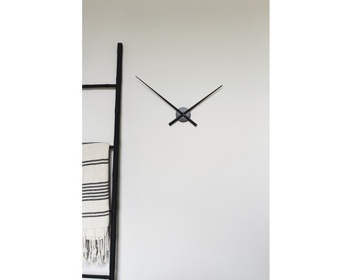 Nástenné hodiny s ručičkami vedľa rebríka s uterákom