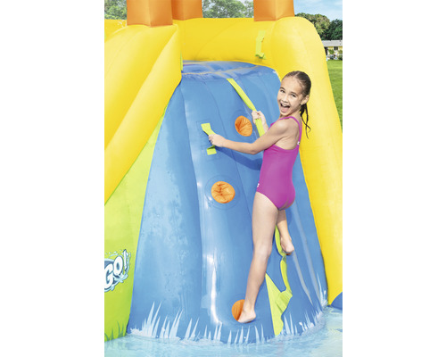 Dievča lezie na nafukovacej vodnej šmýkačke s lezeckou stenou