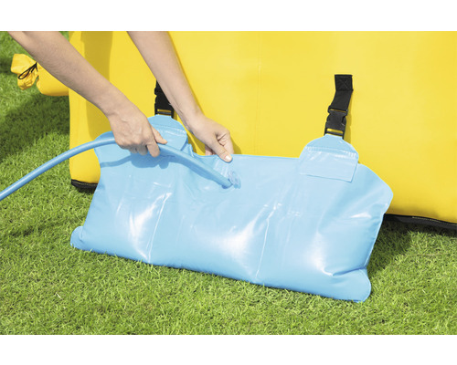 Osoba plní vodný vak na zaťaženie skákacieho hradu pomocou vodnej hadice