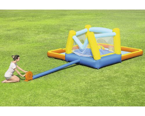 Nafukovací skákací hrad s bazénom na záhrade so ženou, ktorá ho nafukuje.