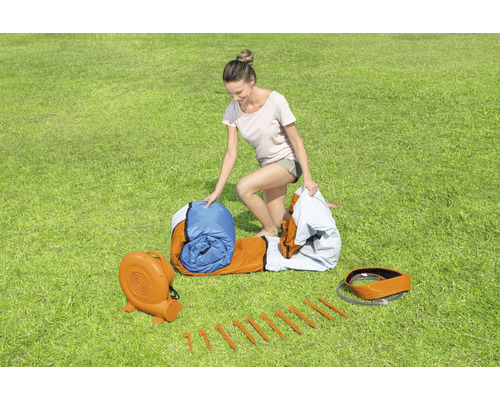 Nafukovací skákací hrad s dúchadlom, kolíky a ženou na trávniku