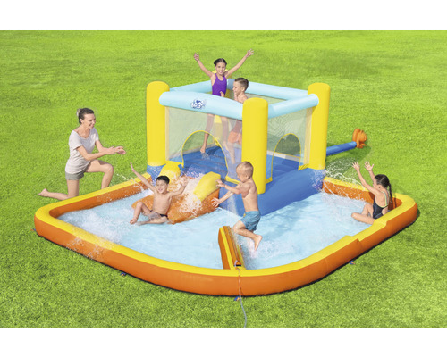 Nafukovací vodný park so šmýkačkou a bazénom na záhrade s hrajúcimi sa deťmi.