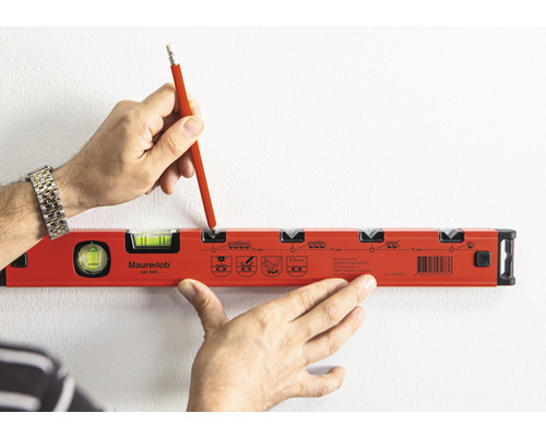 Osoba označuje ceruzkou miesto na stene pomocou vodováhy.