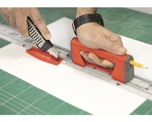 Osoba reže papier s rolovacou rezačkou a rezacím pravítkom