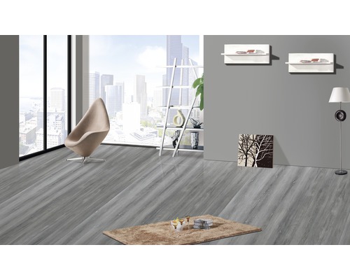 Svetlá miestnosť so sivou drevenou podlahou, kreslom a kobercom