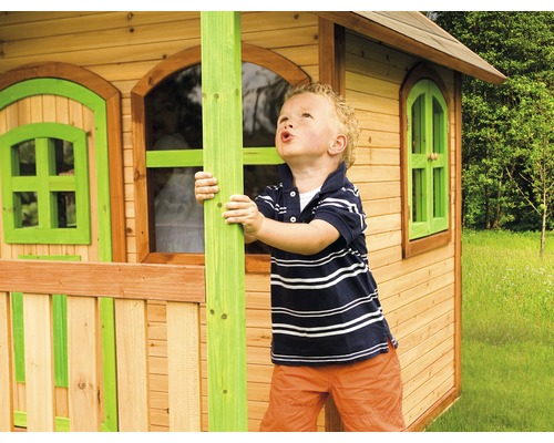 Chlapec sa hrá pred dreveným hracím domom s oknami