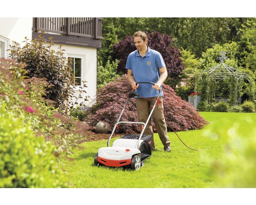 Muž používa kosačku na trávu v záhrade.