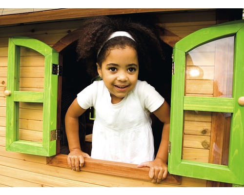 Dieťa sa pozerá z okna dreveného hracieho domčeka.