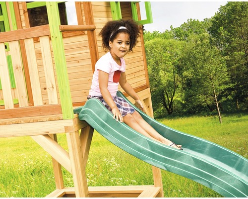 Dievča sa kĺže na šmýkačke na hracej veži v záhrade