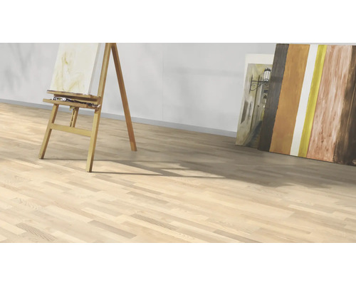 Svetlá drevená podlaha s maliarskym stojanom a plátnami