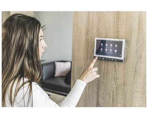 Žena ovláda dotykový displej interkomu na drevenej stene