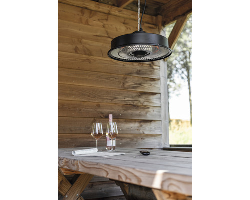 Scéna so stropným ohrievačom nad dreveným stolom s vínom a novinami v záhradnom domčeku