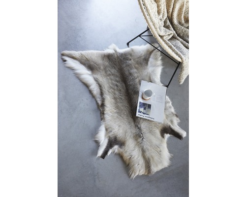 Dekoratívna sobí koža na podlahe vedľa stoličky a časopisu.