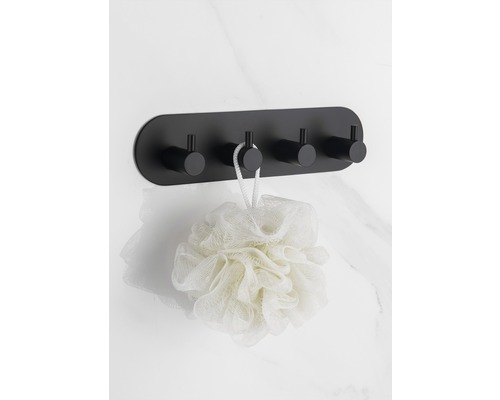 Čierny nástenný vešiak so štyrmi háčikmi a kúpeľovou hubou na mramorovej stene