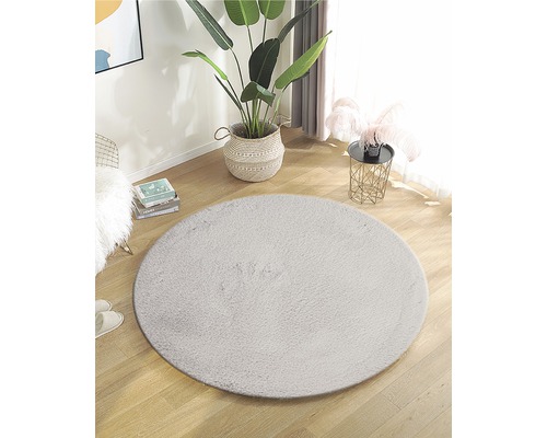 Zariadenie s okrúhlym kobercom z umelého vlákna na drevenej podlahe vo svetlej miestnosti.