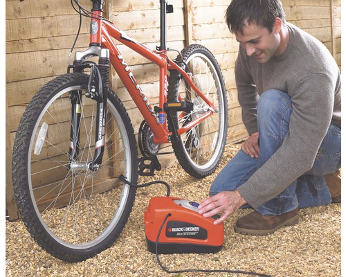 Muž hustí pneumatiku bicykla pomocou vzduchového kompresora Black and Decker