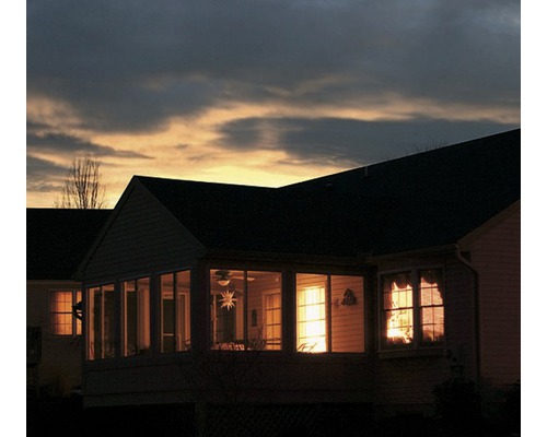 Večerný pohľad na dom s osvetlenými oknami a terasou