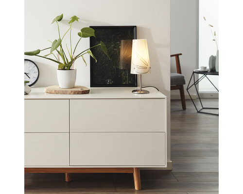 Obývacia izba s komodou, stolnou lampou, izbovou rastlinou a dekoráciou