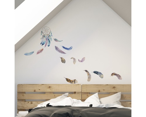Spálňa s nástennou nálepkou lapača snov a peria nad drevenou posteľou