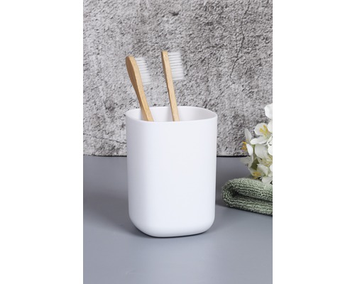 Dve zubné kefky v bielom pohári na zubné kefky
