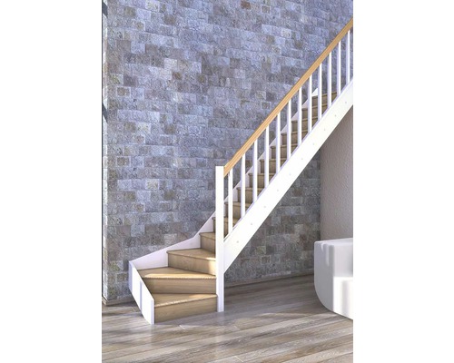 Schodisko s drevenými stupňami a bielym zábradlím pred kamennou stenou