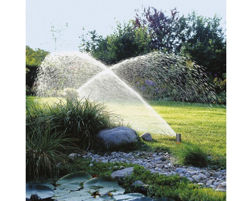 Zavlažovanie záhrady s trávnikovým postrekovačom v prevádzke na trávniku.